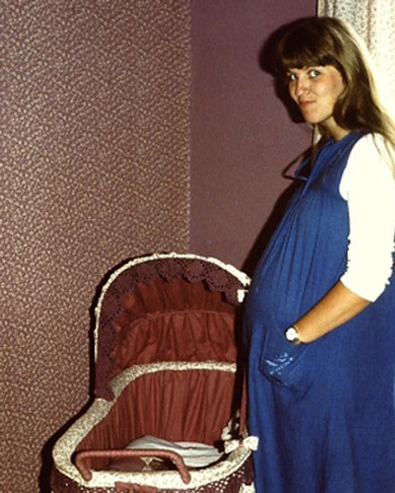 Pregnant lady standing over cot