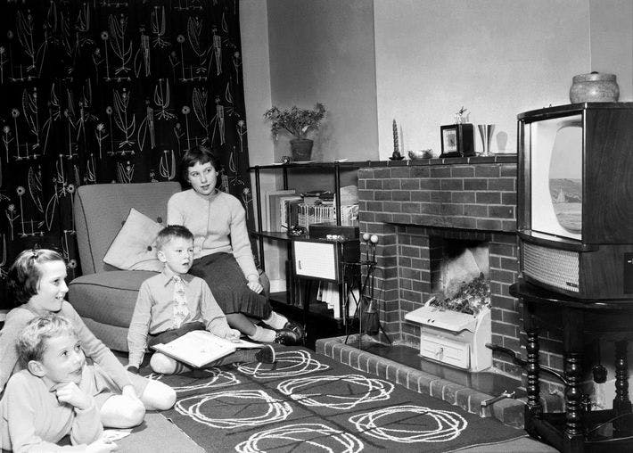 Black and White image of family sitting around a television